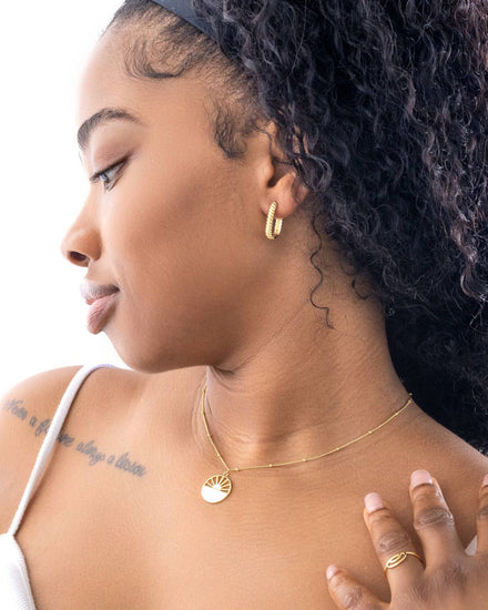 Black female wearing twisted rope earrings from Jewmei, the Sun will Shine again necklace from Jewmei and the New Beginnings Rainbow ring from Jewmei.