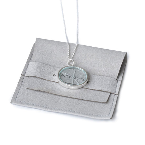 Jewmei Shatter the Glass Ceiling necklace laying on top of a silver jewelry pouch.